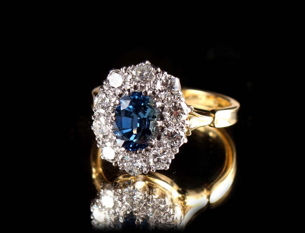 An 18ct yellow gold sapphire & diamond oval cluster ring, the oval cut sapphire weighing