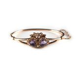 A late Victorian unmarked yellow gold amethyst & seed pearl hinged bangle, with twin heart shaped