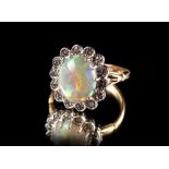 A yellow gold opal & diamond cluster ring, the oval opal weighing an estimated 2.62 carats, set