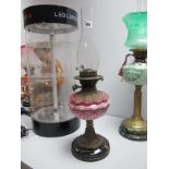 A XIX Century Oil Lamp, with pink glass well, brass support, black terracotta base.