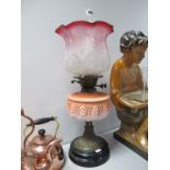 An Early XX Century Oil Lamp, with orange tinted glass wall, brass support, black terracotta base.