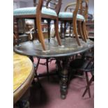 An Ercol Dark Elm Dining Table, oval top with concealed leaf, on ring turned and baluster 'X'