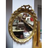 An Oval Wall Mirror in Gilt Wood Frame, with applied plaster mounts.