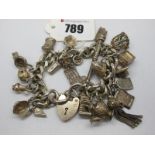 A Curb Link Charm Bracelet, to heart shape padlock clasp, suspending numerous novelty charm