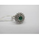 A Modern 18ct White Gold Emerald and Diamond Set Cluster Ring, the central circular emerald claw set