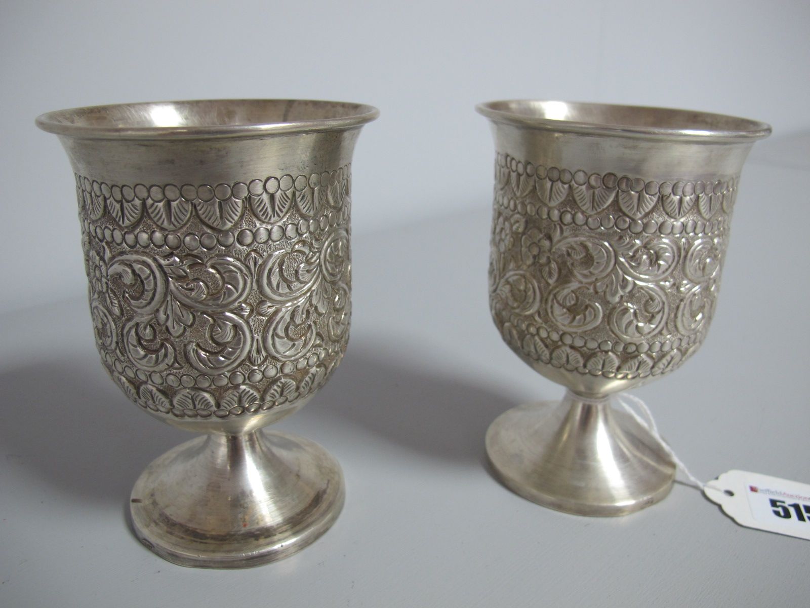 A Pair of Goblets, each detailed in relief with foliate leaf scrolls, on plain circular spreading