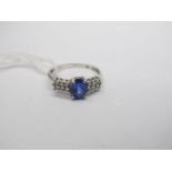 An 18ct White Gold Tanzanite and Diamond Set Ring, oval four claw set to the centre, between two row