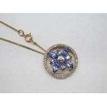 A Tanzanite and Diamond Openwork Pendant, claw set to the centre, of flowerhead design, within