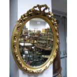 An Oval Wall Mirror in Gilt Wood Frame, with applied plaster mounts.