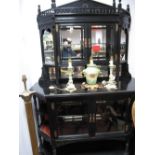 A XIX Century Ebonised Cabinet, with arched galleried top, twin glazed doors, open shelves, the base