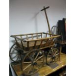 An Early XX Century Pine and Fruitwood Child's Pulley Cart, with slatted sides, iron corner