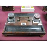 A XIX Century Walnut Desk Stand, with brass handle, ink bottles, on gilded brass bun feet.