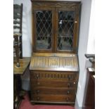 An Oak Bureau, with lead glazed upper doors, linen fold fall front, knulled upper drawers over three