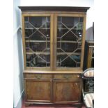 A Mahogany Book Cabinet, with dentil and stepped cornice, astragal glazed doors, over twin drawers