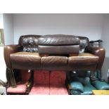 A Three Seater Brown Leather Settee, on squat bun feet, length 240cm, and a matched pouffe. (2)