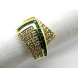 An Emerald and Diamond Set Cocktail Ring, of tapered crossover design, with channel set highlight,