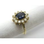 A Sapphire and Diamond Cluster Dress Ring, oval four claw set to the centre within border of