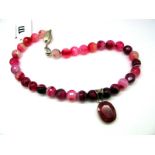 A Modern Polished Pink Hardstone Bead Necklace, suspending large oval ruby panel pendant, collet