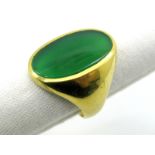 A Gent's Ring, the elongated green oval panel collet rubover set, between tapering shoulders,