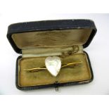 A Mother of Pearl Heart Bar Brooch, claw set to the centre between bifurcated shoulders and plain