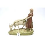 A Royal Dux Pottery Model of a Girl Holding a Goat on a Lead, upon a naturalistic oval rocky base,