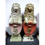 A Pair of Painted Composite Stone Standing Lions, each holding a shield, upon rectangular bases,