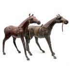 Two Mid XX Century Leather Bound Horses, in standing poses, one wearing a saddle, 62cm high.
