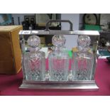 An Edwardian Three Bottle Tantalus, in silver plated carrying frame with key.