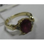 A Ruby Ring, oval claw set to the centre, between triangular inset shoulders, stamped "14K".