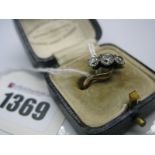 A Three Stone Diamond Ring, the graduated old cut stones claw set between crossover shoulders.