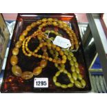 A Single Strand Graduated Amber Coloured Bead Necklace; together with two further bead necklaces. (