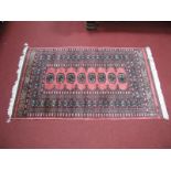 A Middle Eastern Tasseled Wool Rug, with eight central motifs on pink ground and geometric border,