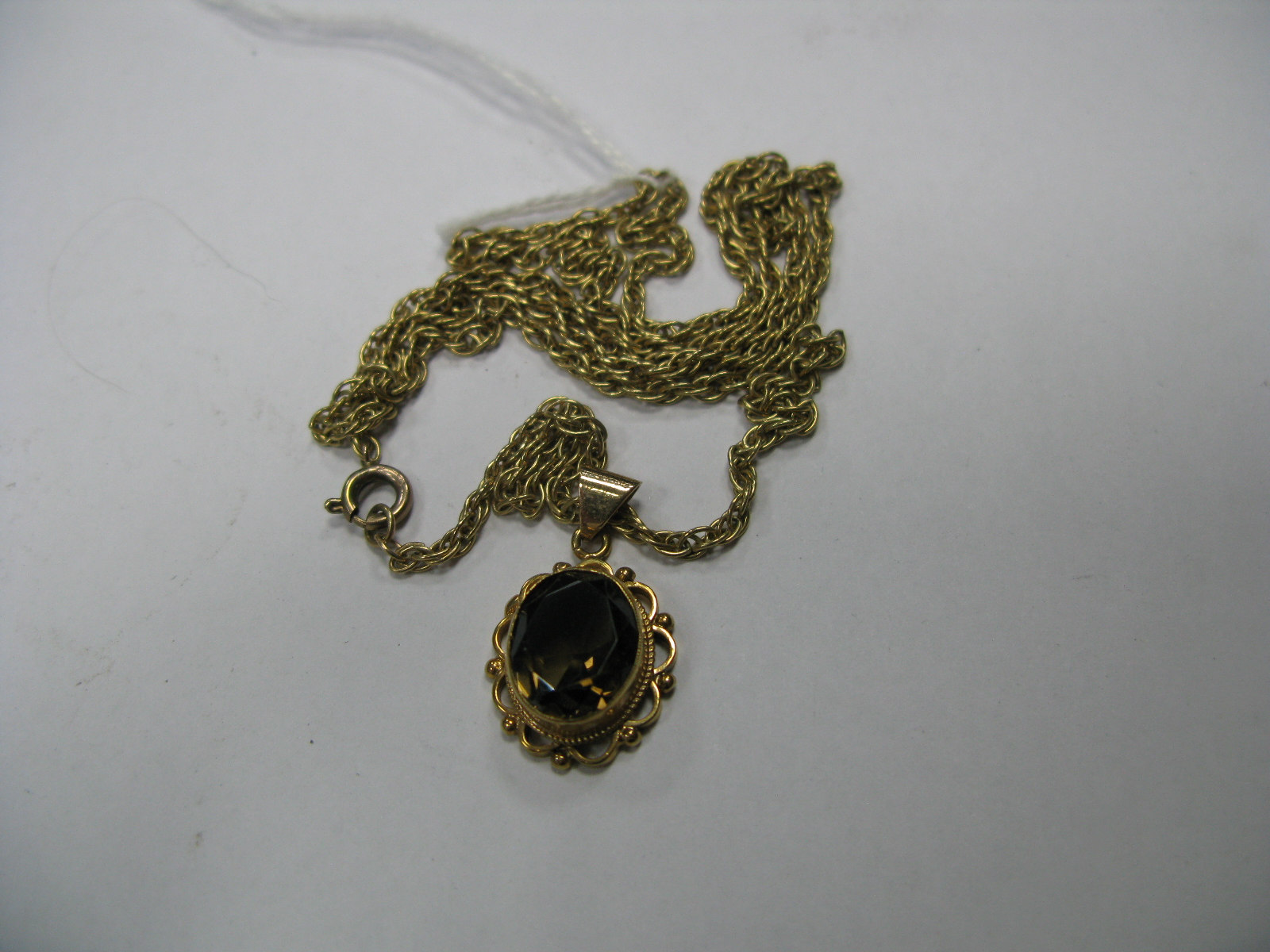 A 9ct Gold Single Stone Pendant, collet set, on a chain.