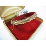 A 9ct Gold Bangle, of bamboo design, hinged to snap clasp.