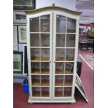 A Modern Painted Pine Display Cabinet, moulded arched cornice with finial, above twin glazed doors