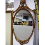 An Oval Bevelled Wall Mirror, the classical frame moulded with swags, trophy and pendant drops.