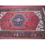 A Persian Style Wool Rug, with a red-pink centre and geometric decoration, tassel ends, 183 x