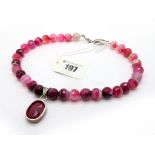 A Modern Polished Pink Hardstone Bead Necklace, suspending large oval ruby panel pendant, collet