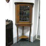 An Oak Corner Cupboard, with lead glazed single door, triangle undershelf, sabre legs.