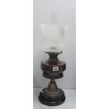 An Oil Lamp, circa 1900 with black glazed terracotta base and ruby glass well.