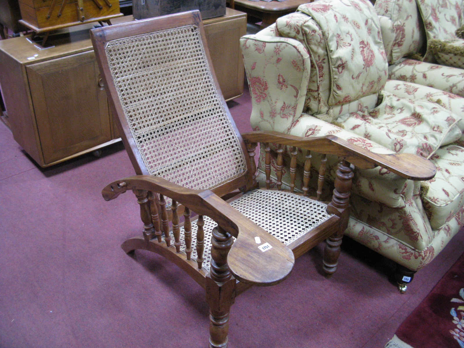 A Teak Reclining Plantation Chair, with a caned back and seat, on turned forefront legs.