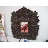 An Oriental Carved Hardwood Framed Wall Mirror, featuring dragons, figures and temple lions, 51.