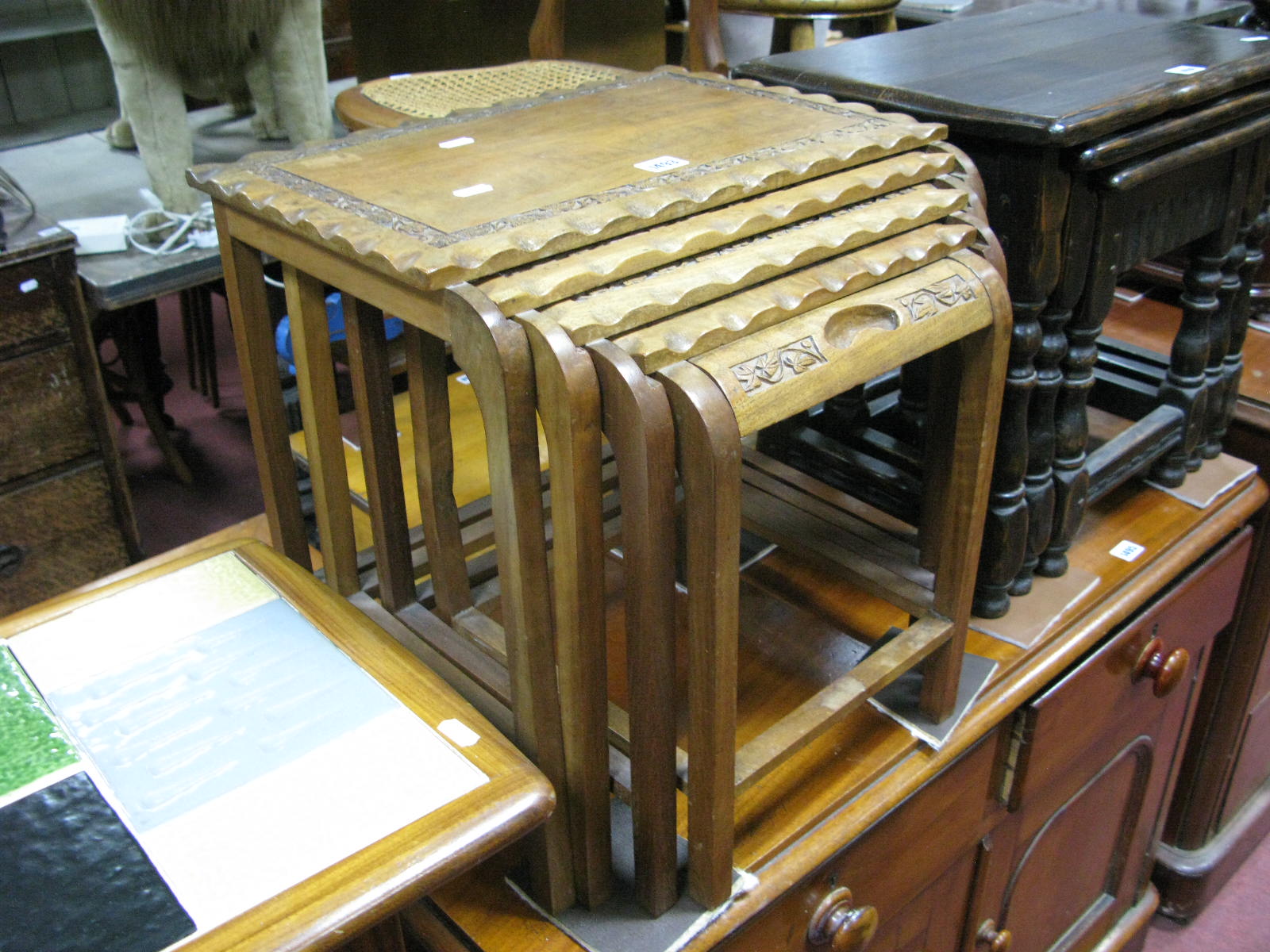 A Hardwood Nest of Five Tables, four with crimped ends and carved foliate borders, on stretchered