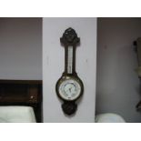 An Early XX Century Oak Aneroid Barometer, shaped top, with a carved flower, temperature gauge,