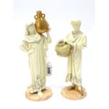 A Pair of Royal Worcester Figures of Cairo Water Carriers, each holding a large urn, their cream