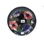 A Moorcroft Pottery Dish, of circular form, painted in the 'Anemone' pattern against a dark blue