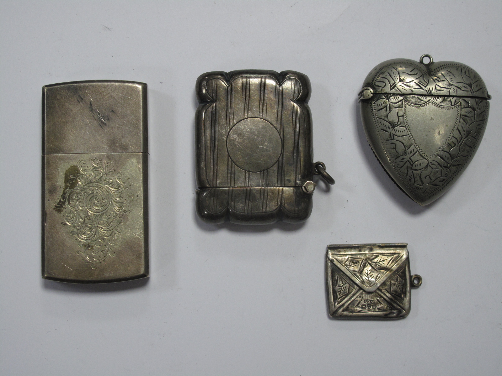 A Hallmarked Silver Vesta Case, engine turned; together with a heart shape vesta case, a lighter and