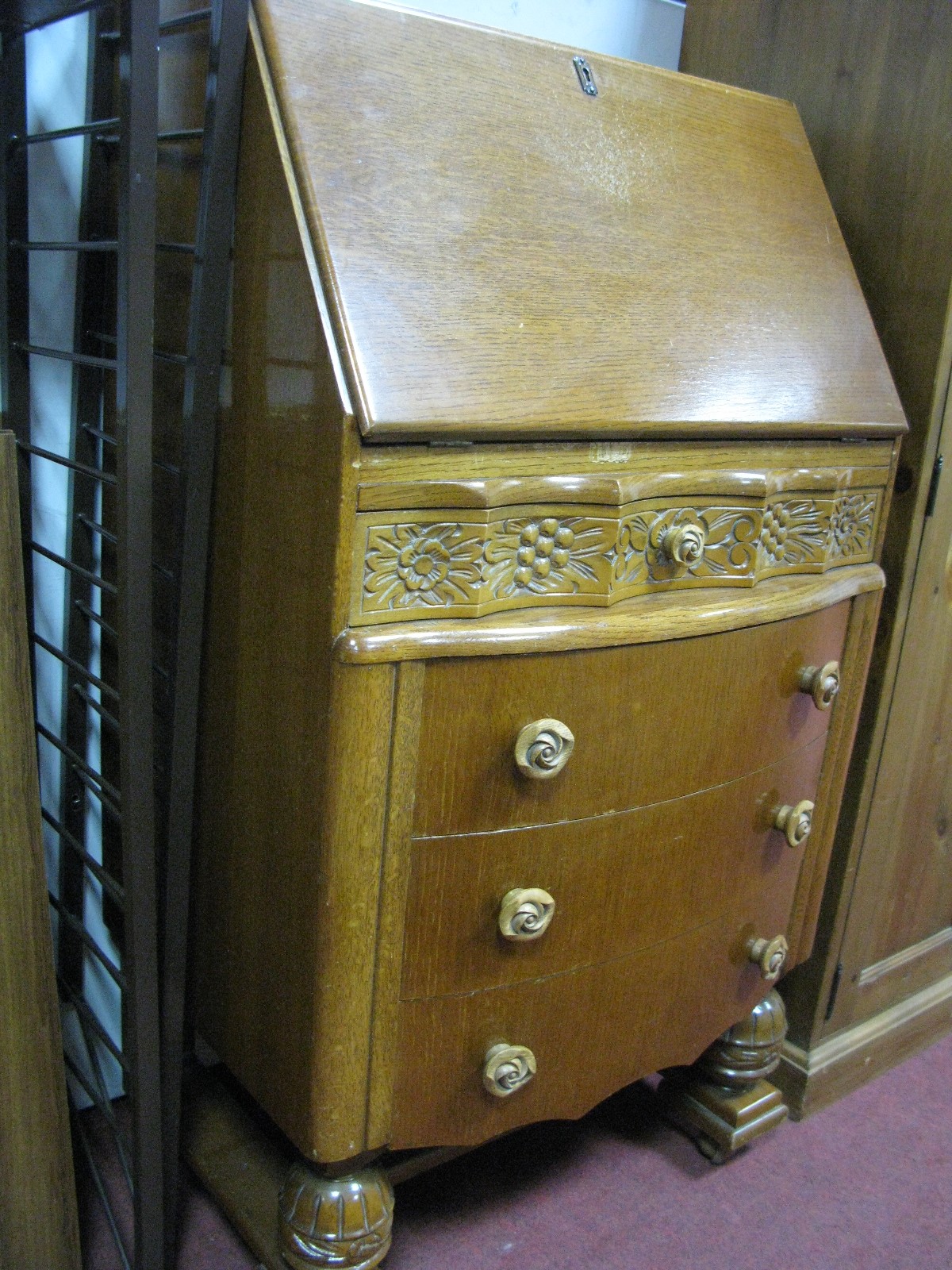 A Mid XX Century Oak Bureau with a fall front, shaped top drawer over three long drawers, on cup