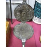 A Cast Iron Waffle Maker, with hexagonal pictorial press motifs, 54cm long when closed.