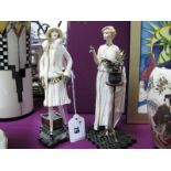 A Pair of Chine Figurines of Art Deco Ladies, each on bronzed metal base with tree/plant.